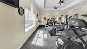 A gym with ceiling fans, exercise equipment, and a large window. - Orlando Condo 6448 Getaway: 3BR Near Disney Magic (Orlando)