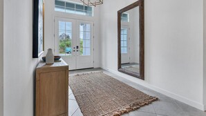Un couloir avec un grand miroir, une console en bois et un tapis à motifs.
