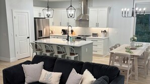 A modern kitchen with white cabinets, stainless steel appliances, and pendant lighting.