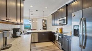 A modern kitchen with dark cabinets, stainless steel appliances, and a marble countertop. - Private Pool & Dock, Charlotte County Villa 5890 (Charlotte County)