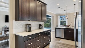 A modern kitchen with dark cabinetry, a marble countertop, and stainless steel appliances. - Private Pool & Dock, Charlotte County Villa 5890 (Charlotte County)