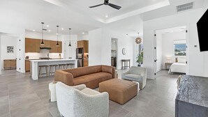 A spacious living area with a large brown sectional sofa, two grey armchairs, and a coffee table. A ceiling fan and recessed lighting are visible. - Charlotte County Villa 5892 - Pool Home Retreat (Charlotte County)