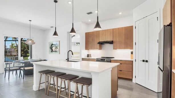 A modern kitchen with a large island, wooden cabinets, and pendant lighting. - Charlotte County Villa 5892 - Pool Home Retreat (Charlotte County)