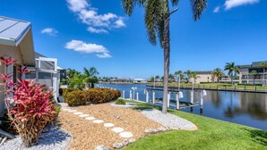 A modern building with a well-maintained garden, a clear view of the water body, and a palm tree.
