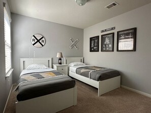 A bedroom with two beds, a nightstand, a lamp, and three framed pictures on the wall. - Charming house in The Woodlands - Creekside (Tomball)