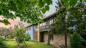 Ein zweistöckiges Haus mit einer Steinaußenfassade, einem Balkon und einem Garten.