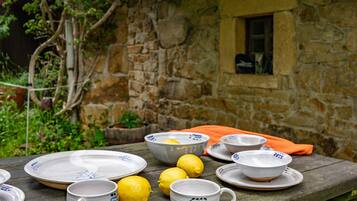 Una mesa de comedor rústica al aire libre con platos de cerámica, tazas y limones.