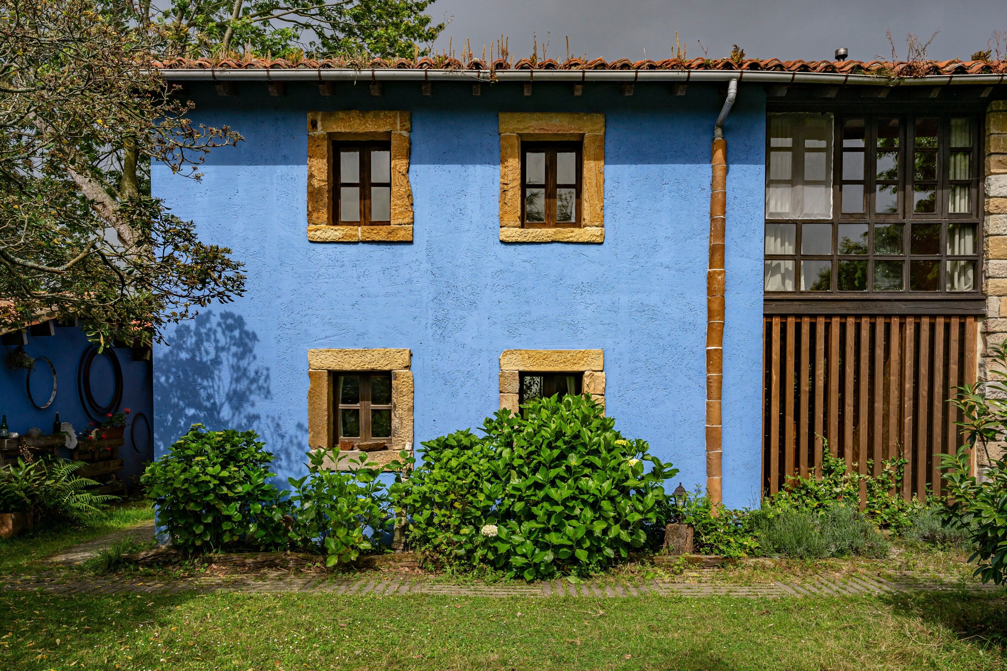Un edificio azul con tres ventanas y una puerta de madera.