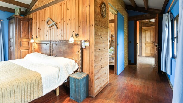 Ein Schlafzimmer mit Holzwänden, einem Bett, Nachttischlampen und einem Holzschrank.