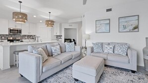 A modern living room with a sofa set, ottoman, and a patterned rug.