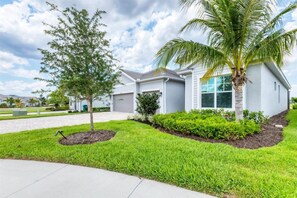 A modern residential building with a well-maintained lawn, a palm tree, and a clear sky.