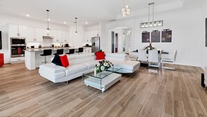 A spacious living area with a white sofa, a glass coffee table, and a dining area with a white table and chairs. - Premier Golf & Pool Retreat – Charlotte County Villa 5902 (Charlotte County)