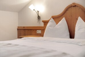 A neatly made bed with white linens, a wooden headboard, and a wall-mounted lamp. - Apartment 'Loderhof Sternenhimmel' with Mountain View, Shared Garden and Wi-Fi (Sand in Taufers)