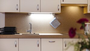 A kitchen with white cabinets, a stainless steel sink, and a countertop with a coffee machine. - Apartment 'Loderhof Blumenwiese' with Mountain View, Shared Garden & Wi-Fi (Sand in Taufers)