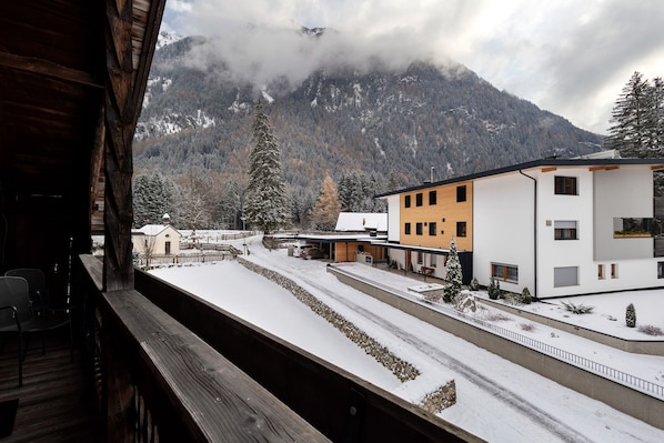 A snowy mountain landscape with buildings and a wooden balcony.