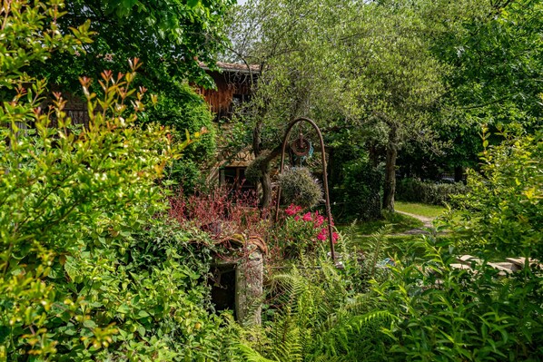 A lush garden with a stone structure, a pathway, and dense foliage.
