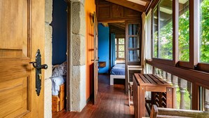 Een houten interieur met een bed, een bankje en een tafel.