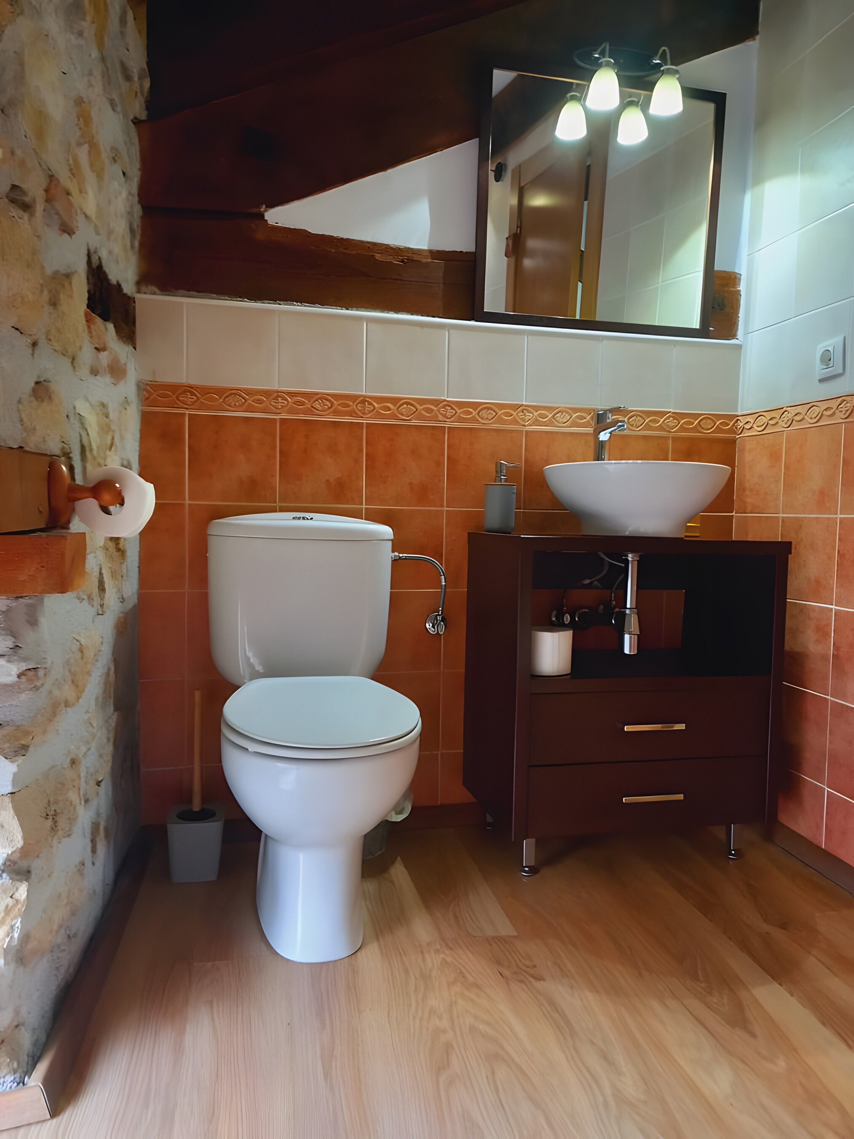 Un baño con inodoro, lavamanos y tocador de madera.