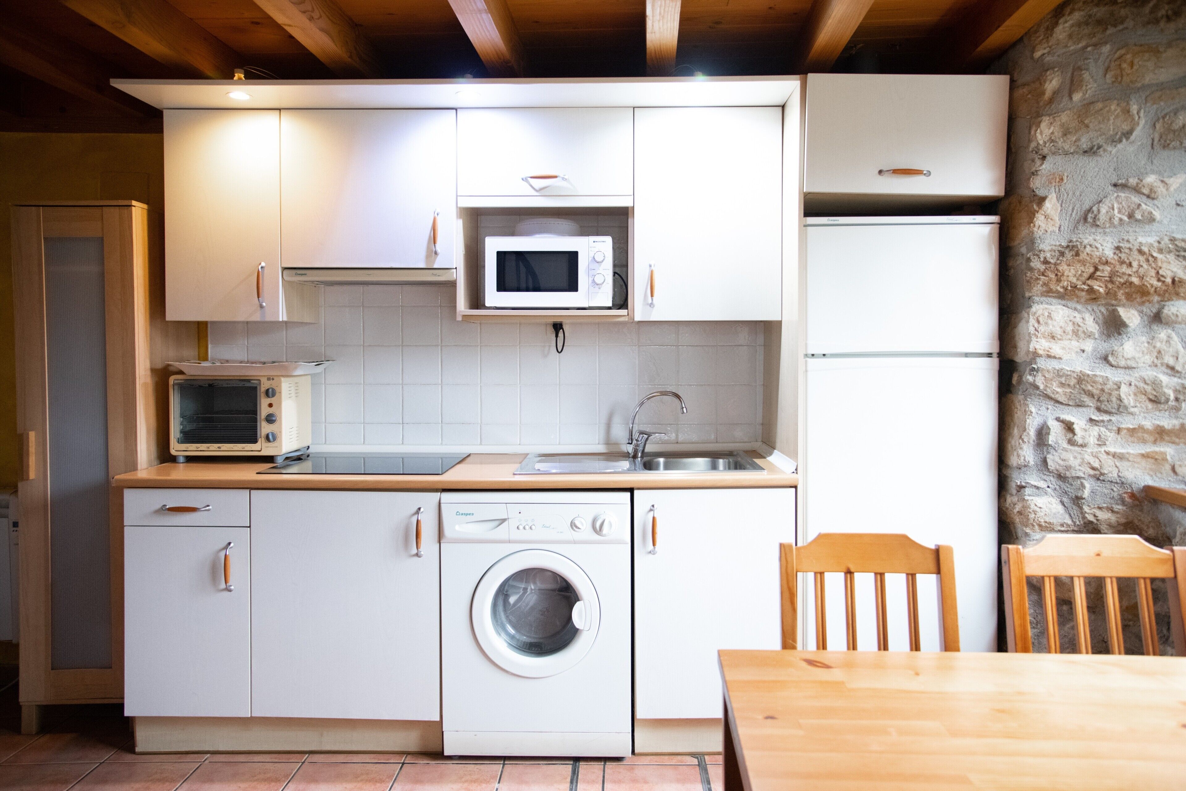A compact kitchen with a washing machine, microwave, and oven.
