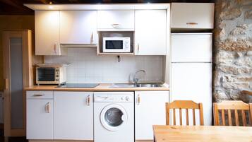 A compact kitchen with a washing machine, microwave, and oven.