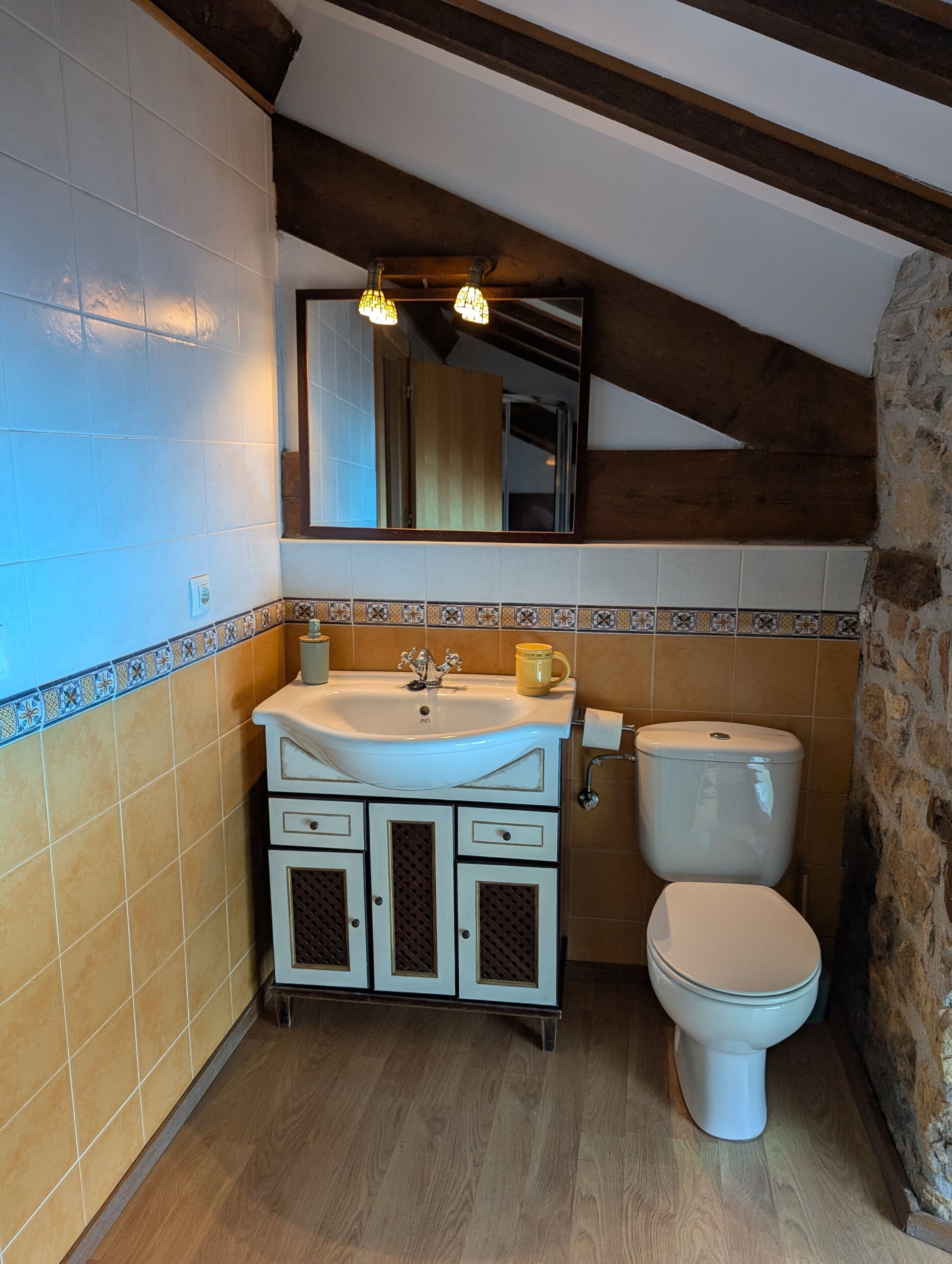 Ein Badezimmer mit einem weißen Waschbecken, einer Toilette und einem Spiegel über dem Waschbecken.