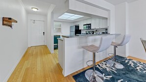 Una cocina moderna con armarios blancos, una isla central con taburetes y vistas al área de estar.