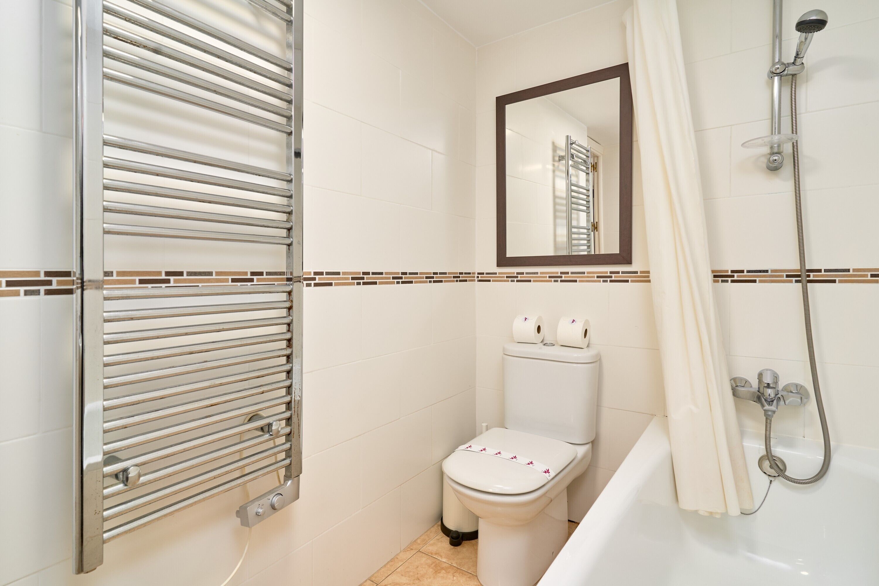 Une salle de bain équipée de toilettes, d’une douche et d’un porte-serviettes.