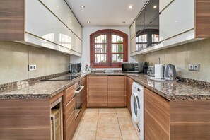 A modern kitchen with granite countertops, wooden cabinets, a built-in oven, a microwave, and a dishwasher.