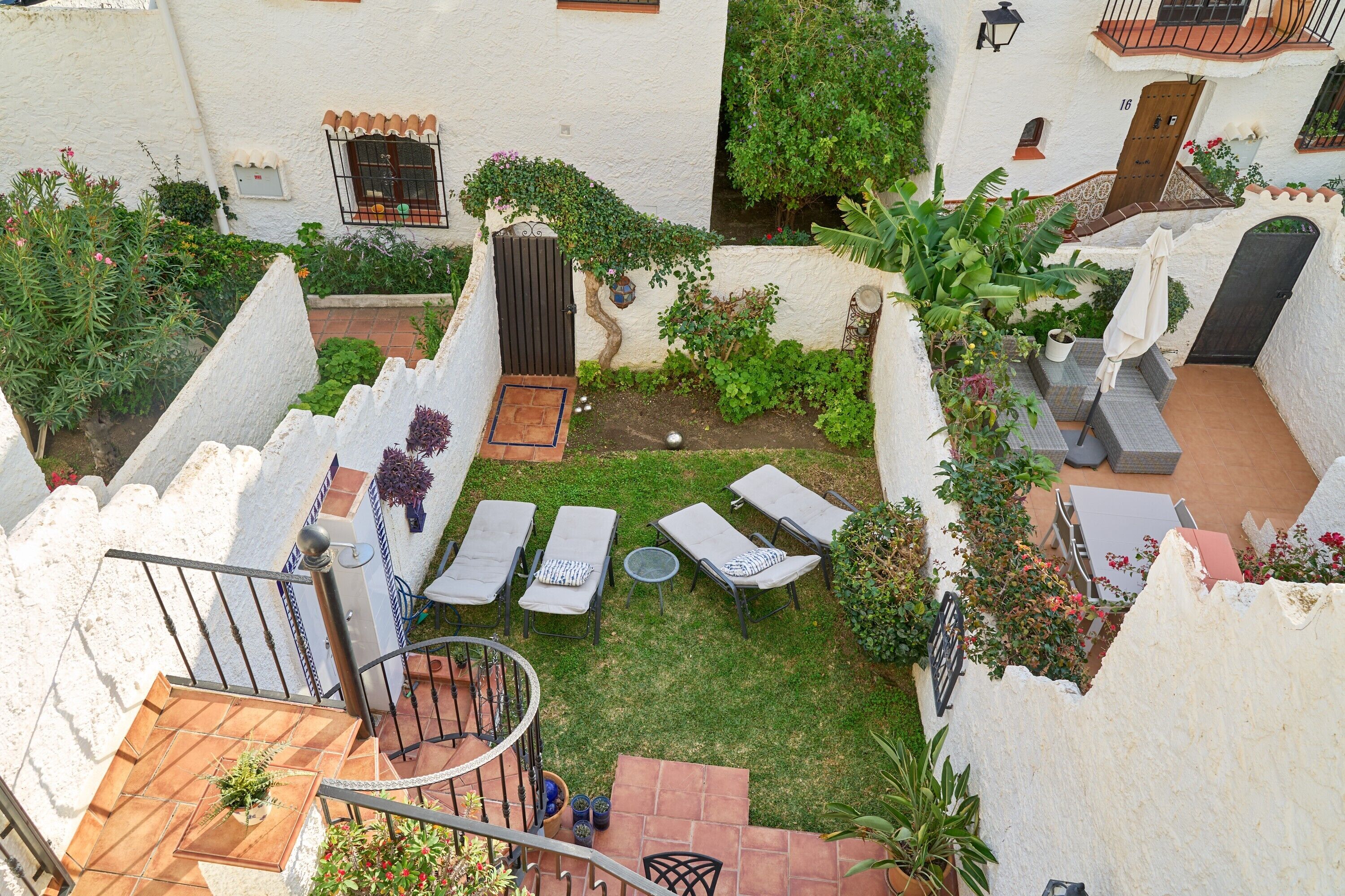 A courtyard with a small garden, outdoor seating, and a staircase.