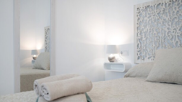 A bedroom with a bed, a bedside table, a lamp, and a decorative wall panel. - Studio Apartment 'Apartamentos Maria' with Wi-Fi and Air Conditioning (Vejer de la Frontera)