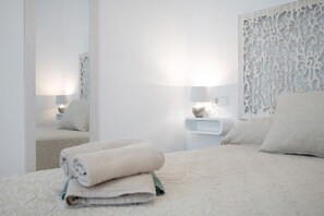 A bedroom with a bed, a bedside table, a lamp, and a decorative wall panel.