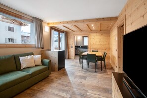 A wooden interior with a sofa, dining table, chairs, and a TV. - Apartment 'Gavia Bormio' with Mountain View, Balcony and Wi-Fi (Bormio)