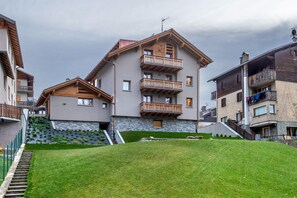 Ein mehrgeschossiges Gebäude mit Balkonen, einer Stein-Fassade und einer Rasenfläche davor.