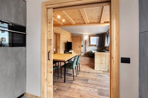 A wooden interior with a dining area, kitchen, and living space. - Apartment 'Gavia Bormio' with Mountain View, Balcony and Wi-Fi (Bormio)