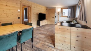 Un interior de madera con una mesa de comedor, sillas, un televisor y una kitchenette.