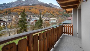 Un balcón con baranda de madera con vistas a un pueblo y montañas.