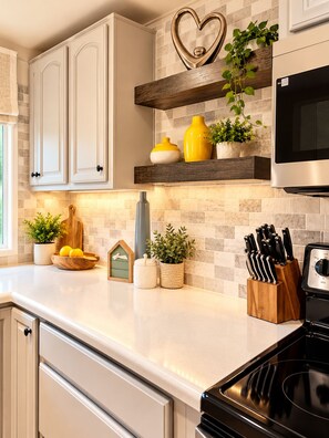 A kitchen with white cabinets, a heart-shaped decoration, and various kitchen items on the counter. - Private marsh views -under mossy oaks, minutes to beaches & downtown (Fernandina Beach)