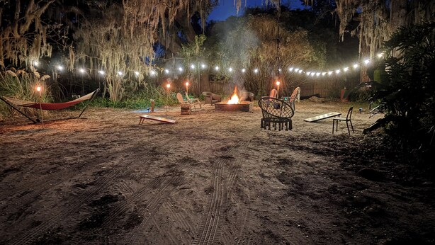 A sandy outdoor area with a hammock, chairs, a fire pit, and string lights. - Private marsh views -under mossy oaks, minutes to beaches & downtown’s  (Fernandina Beach)