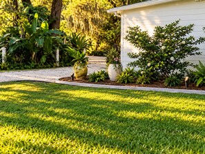 A well-maintained garden with a variety of plants and a pathway leading to a white building.