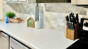 A kitchen with white cabinets, a microwave, a knife block, and decorative items on the counter. - Private marsh views -under mossy oaks, minutes to beaches & downtown’s  (Fernandina Beach)