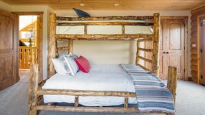 A rustic wooden bunk bed with a white mattress and pillows, a striped blanket, and a wooden headboard.