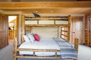 A rustic wooden bunk bed with a white mattress and pillows, a striped blanket, and a wooden headboard.