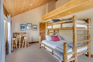Une chambre rustique avec un lit superposé en bois, un plafond haut et une petite table en bois.