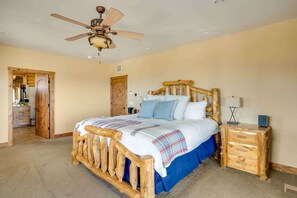 A bedroom with a wooden bed, a nightstand, a ceiling fan, and a door leading to another room.