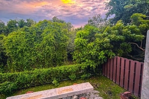 A garden with a wooden bench, a metal fence, and dense greenery. - Royale Riviera Resort Private Pool Villas (Langkawi)