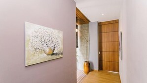 A hallway with a wooden floor, a painting on the wall, and a wooden door. - Royale Riviera Resort Private Pool Villas (Langkawi)