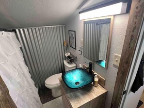 A bathroom with a white toilet, a glass sink, and a shower curtain. - Bar, pool table, dart board and 2 bedrooms, what else do you need? (Redmond)