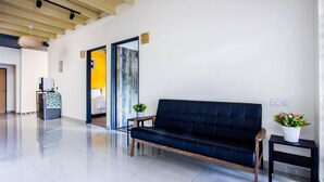 Ein modernes Wohnzimmer mit einem dunklen Sofa, einem kleinen Beistelltisch mit einem Topf und einem Kühlschrank mit bunten Magneten.