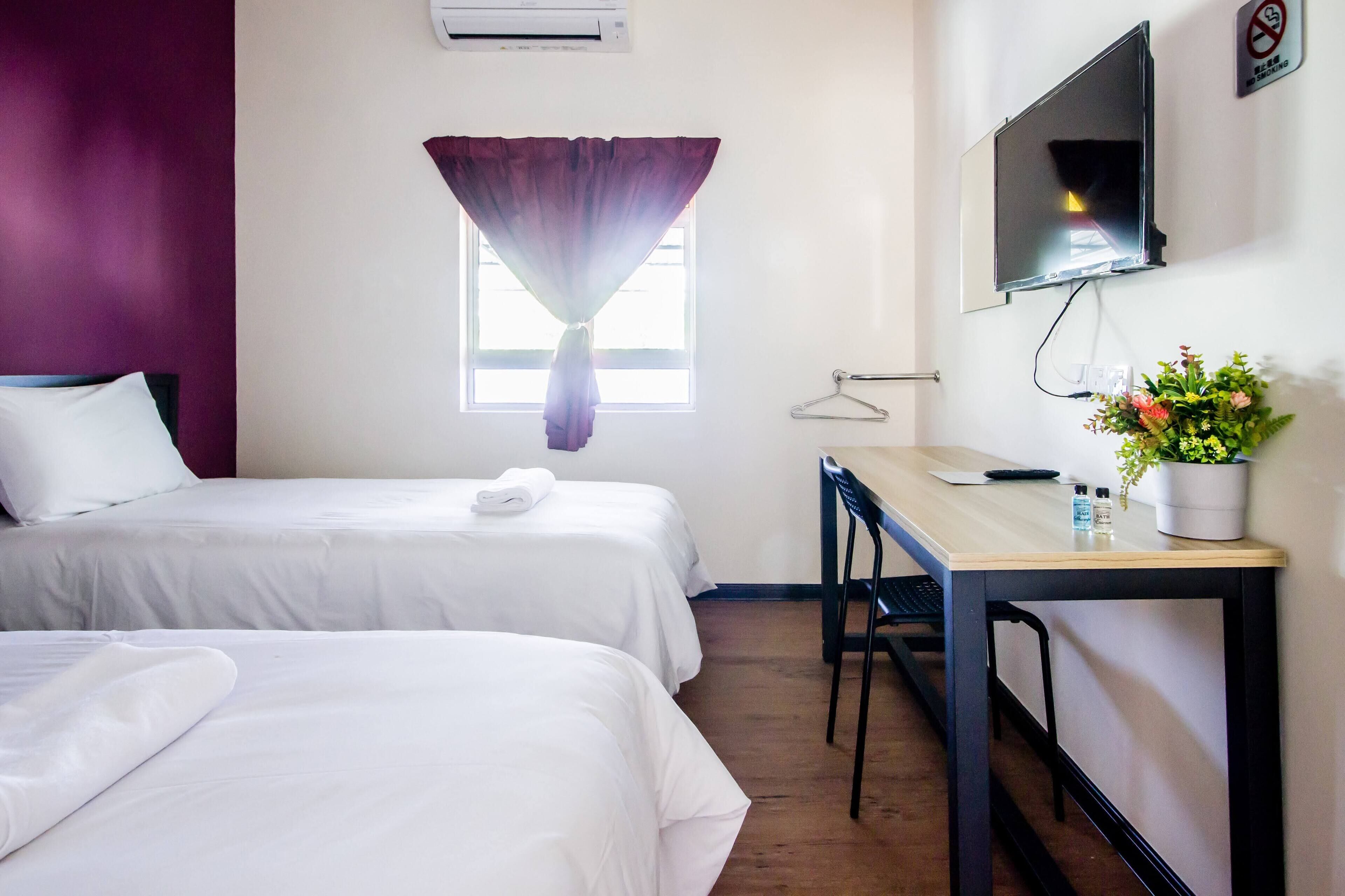 Une chambre d’hôtel avec deux lits, un bureau, une télévision et une fenêtre avec des rideaux.