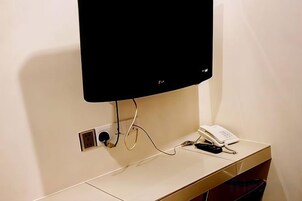 Un televisor de pantalla plana montado en la pared, un teléfono y un enchufe en una encimera.